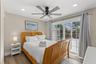 Owner's edroom with luxury vinyl plank flooring, ceiling fan, and sliding glass doors opening directly to the pool area.