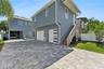 The rear garage has two garage doors, an exterior staircase, and a paved parking area.