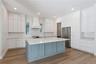 The main kitchen features a blue island, white cabinetry, a statement range hood, and stainless steel appliances.