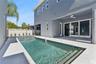 The pool sits beside a paved deck and covered rear patio, creating an inviting outdoor setting.
