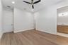 This bedroom includes a shuttered window, ceiling fan, and a view into the built-in closet.