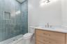 Blue shower tile and a wood-toned vanity add color and warmth to this bathroom.