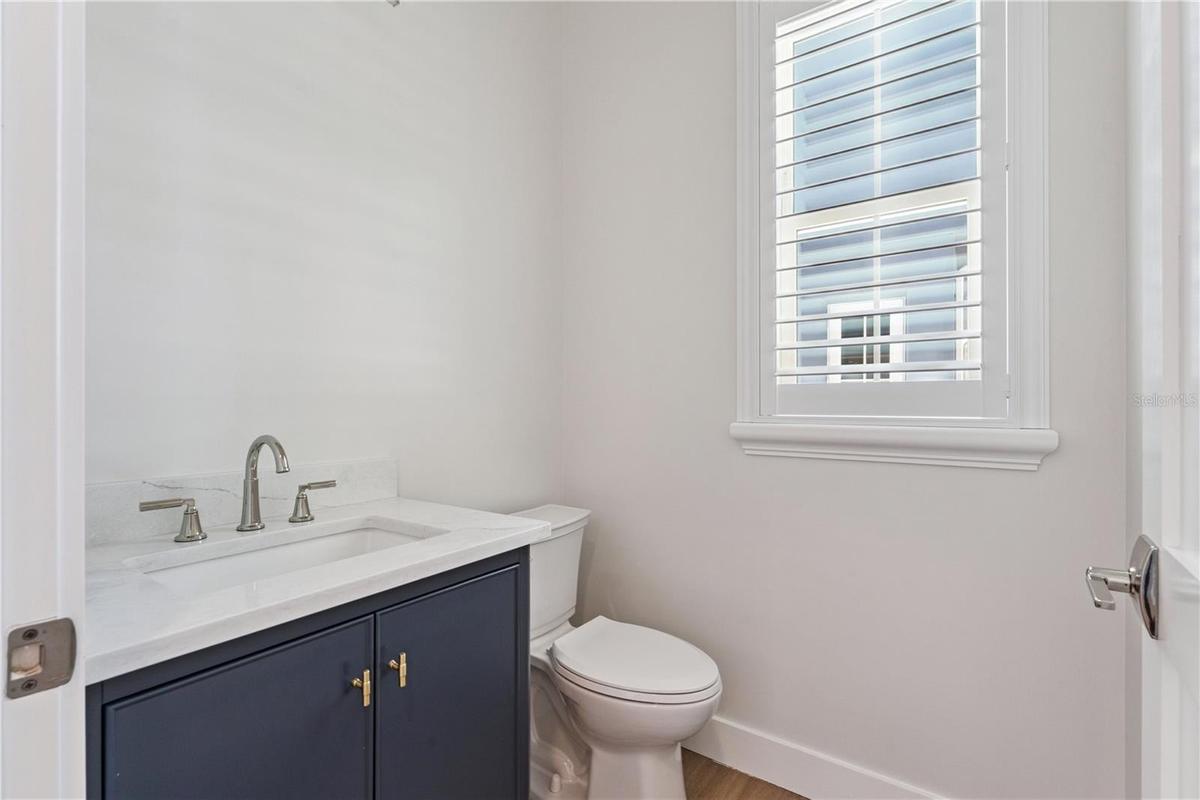 A navy vanity, light countertop, and shuttered window give this powder room a crisp finish.