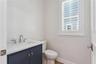 A navy vanity, light countertop, and shuttered window give this powder room a crisp finish.