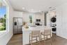 Virtually Staged - The guest-suite kitchen includes a white island, stainless steel appliances, and a stacked washer and dryer.