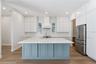 Main kitchen at 3456 Fairway Ln with a blue island, white counters, range hood, and stainless steel appliances.