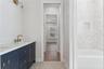 A navy double vanity pairs with patterned flooring and a tub-and-shower combination.