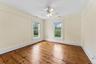 Wood-finish flooring, overhead ceiling fan, white trim, and two windows