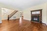 Hardwood flooring throughout, featuring a detailed wooden staircase and an ornate fireplace with an intricate surround