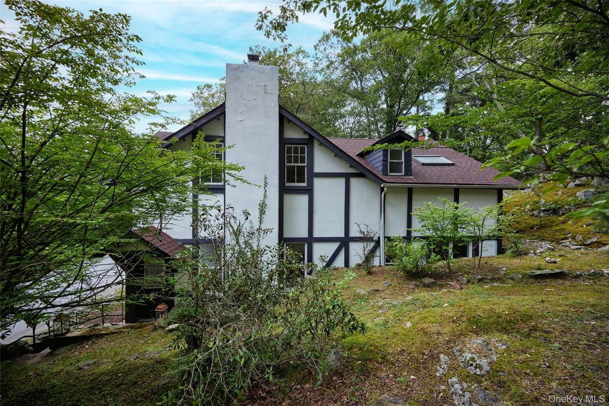 Back of property with a chimney, roof with shingles, and stucco siding