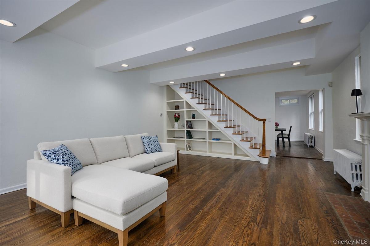 Living room with recessed lighting, radiator heating unit, dark wood finished floors, and stairs