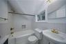 Bathroom featuring tile walls, washtub / shower combination, and lofted ceiling