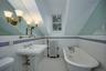 Full bath featuring lofted ceiling, a freestanding bath, radiator heating unit, tile walls, and light tile patterned floors