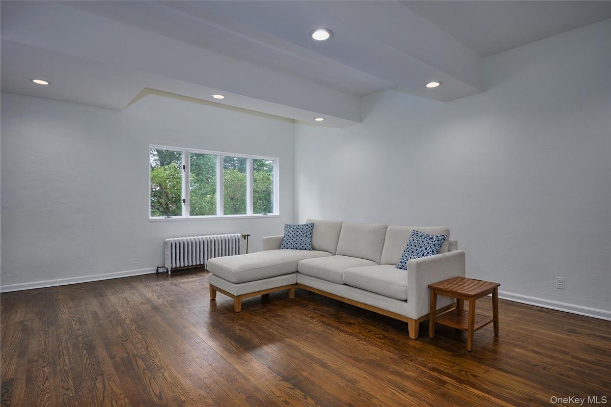 Living area featuring radiator heating unit, dark wood-style floors, and recessed lighting