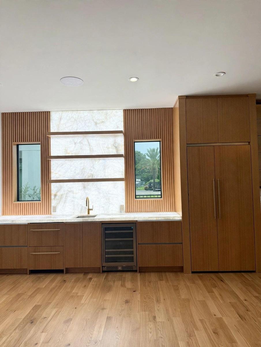 Wood-finish cabinetry with integrated appliances, light-toned countertop, and wood-finish flooring