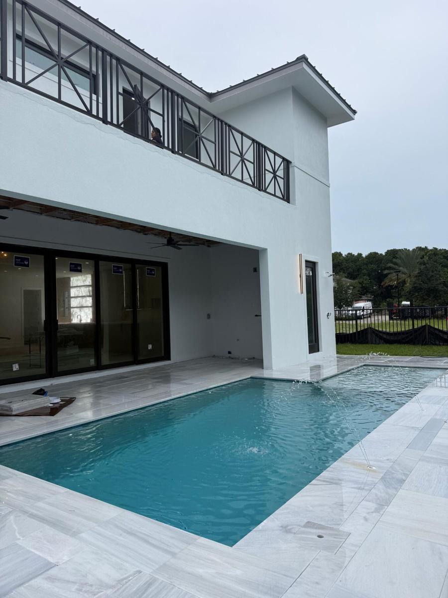 Two-tier swimming pool with an integrated spa, surrounded by white stone pavers