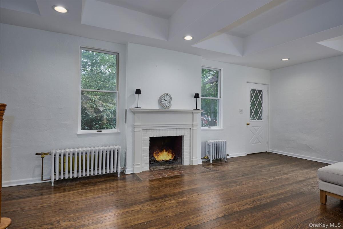 Unfurnished living room featuring radiator, dark wood finished floors, recessed lighting, and a tray ceiling