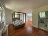 Bedroom with radiator heating unit, hardwood / wood-style floors, a skylight, lofted ceiling, and ensuite bathroom