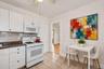 Kitchen with white appliances, gas stove and refrigerator. Enhanced with virutal staging.