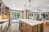 Gourmet kitchen featuring wood-finish flooring, a center island with integrated microwave, white countertops, and glass-paneled upper cabinetry