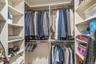 Custom closet system featuring multiple hanging rods, adjustable shelving, and integrated overhead lighting