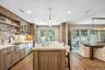 Modern kitchen featuring a large central island, light wood-finish cabinetry, stainless steel appliances, and a farmhouse sink