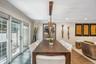 Dark wood finish dining table with a linear chandelier, recessed lighting, and crown molding