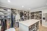 Custom built-in shelving, recessed lighting, crown molding, a central island with storage, and carpeted flooring