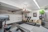 Garage featuring a paneled overhead door, white slat wall, durable tile flooring, and integrated overhead lighting