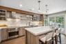 Spacious kitchen featuring a center island with countertop seating, stainless steel appliances, wood-finish flooring, and sliding glass doors