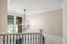 Spherical chandelier, crown molding, wainscoting, tall window, wrought iron balusters