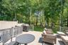 Expansive outdoor deck featuring wood-finish flooring, protective railing, and a private wooded backdrop