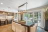Open-concept living area with wood-finish flooring, a contemporary linear chandelier, and expansive sliding glass doors