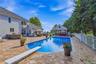 Expansive paver patio with an in-ground pool, diving board, and pool house