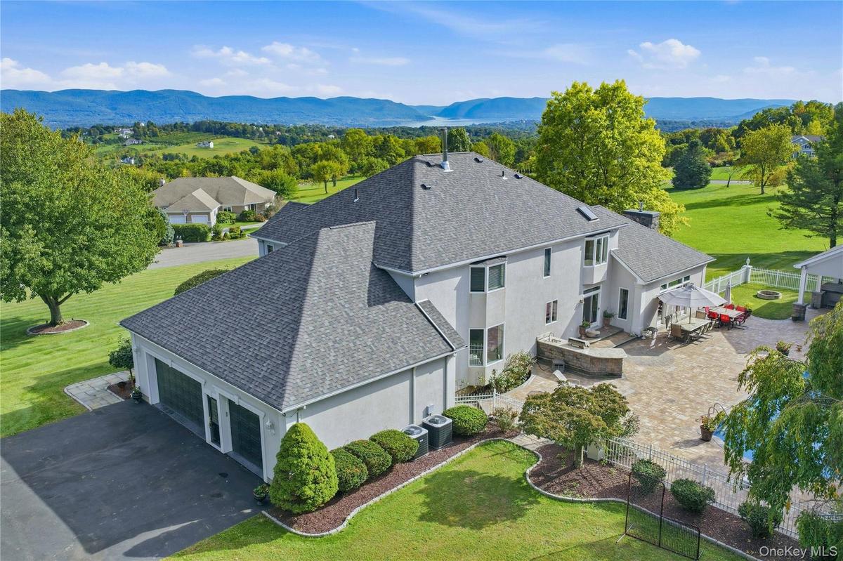 Stucco exterior with multi-level roofline, extensive paver patio, in-ground swimming pool, and dedicated three car garage