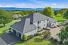 Stucco exterior with multi-level roofline, extensive paver patio, in-ground swimming pool, and dedicated three car garage