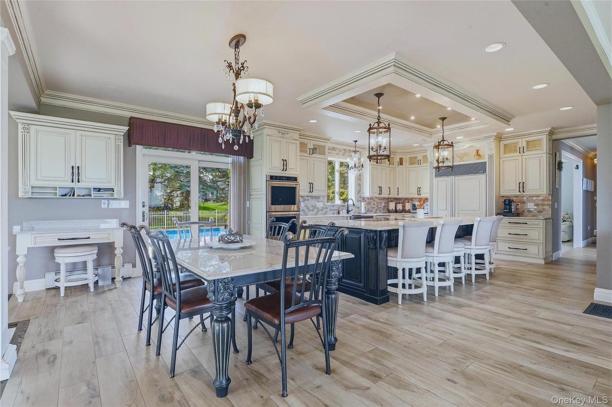 Wood-finish flooring, custom cabinetry, large kitchen island with seating, built-in appliances, quartzite table, and a sliding glass door