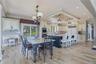Wood-finish flooring, custom cabinetry, large kitchen island with seating, built-in appliances, quartzite table, and a sliding glass door
