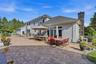 Expansive paver patio with a built-in outdoor kitchen, stone chimney, and stucco exterior