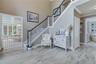Two-story foyer with wood-look flooring, wrought iron staircase, crown molding, and an arched doorway