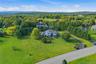 Expansive landscaped grounds with a curved asphalt driveway, mature trees, and a two-story residence featuring a portico entry