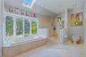 Jetted soaking tub with a bay window, walk-in European shower with a rainfall showerhead, skylight, and recessed lighting, marble flooring