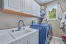 White cabinetry, a utility sink with a matte black faucet, and wood look flooring