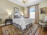 LOVELY GUEST ROOM ON THE OPPOSITE SIDE OF THE HOME WITH HARDWOOD FLOORING, CUSTOM DRAPES, AND NEW FANDELIER LIGHT FIXTURE.