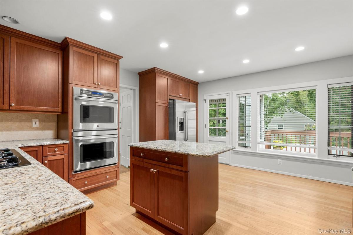 Large eat-in kitchen with rich cabinetry, stainless steel appliances including double ovens. Opens to deck for easy outdoor dining