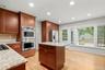Large eat-in kitchen with rich cabinetry, stainless steel appliances including double ovens. Opens to deck for easy outdoor dining