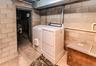 Laundry area featuring a side-by-side washer and dryer, concrete block walls, and exposed utility piping