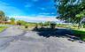 Asphalt driveway with a circular turnaround, surrounded by mature trees and landscaping