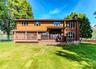 Expansive backyard with a manicured lawn, a multi-level wood deck, and a wood-sided exterior