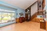 Expansive front window, wood-finish flooring, wood paneling, and a wood staircase with balusters